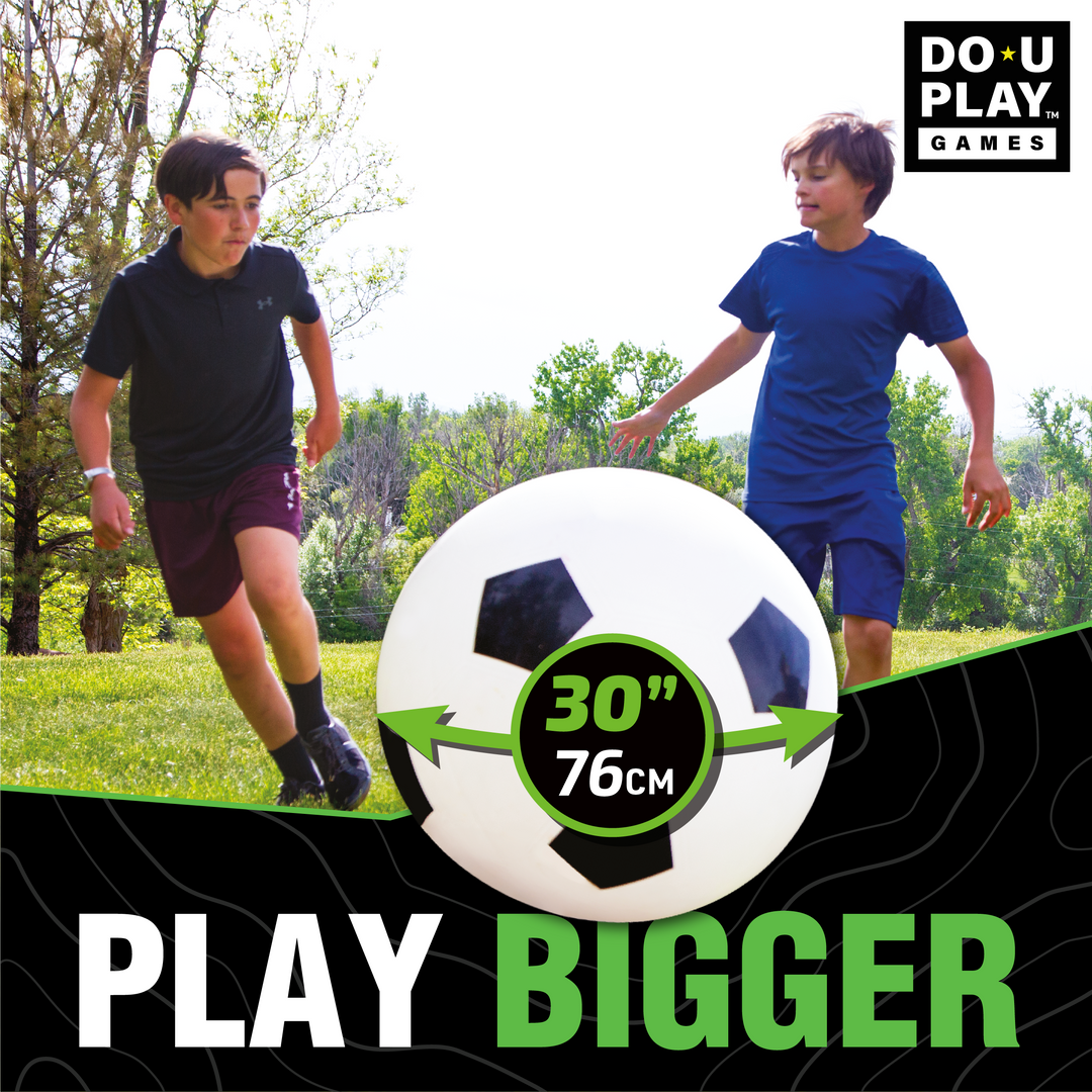 Kids running and chasing jumbo soccer ball at park or playground
