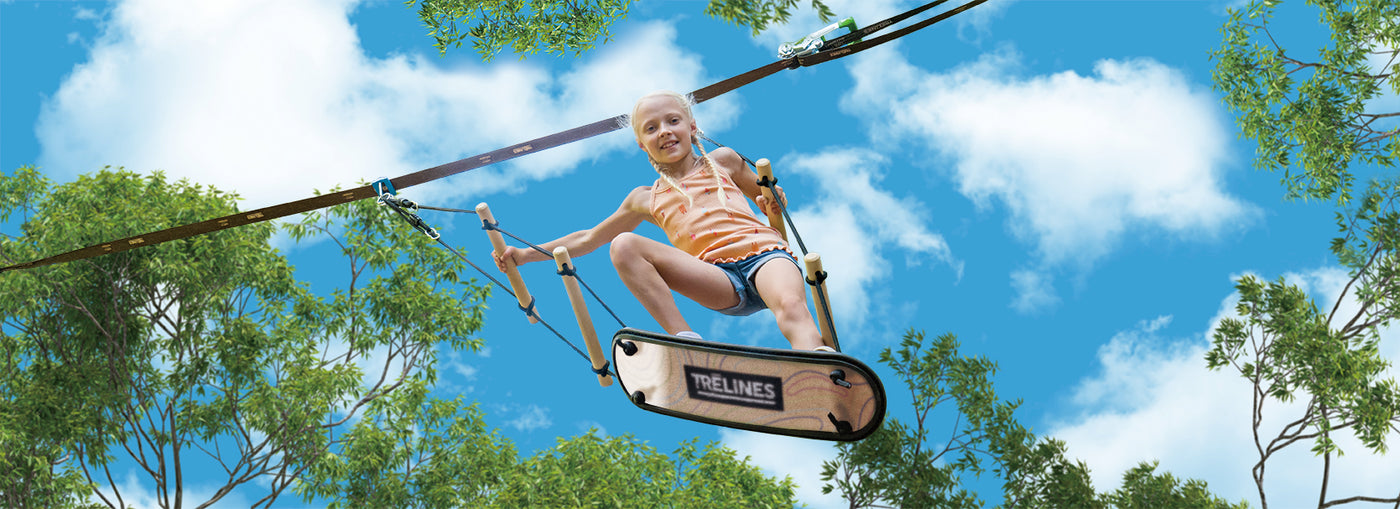 A child riding a Trelines TreBoard between two trees